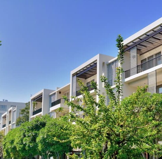 Δέντρα και μπαλκόνια διαμερισμάτων με γαλανό ουρανό