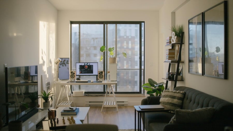 Σαλόνι με καναπέ, τηλεόραση και γραφείο μπροστά σε μεγάλο παράθυρο