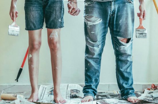 Γυναίκα και άνδρας λερωμένοι με μπογιές σε σπίτι κατά την ανακαίνιση