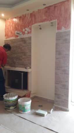 τοποθέτηση πλακιδίων τύπου πέτρας σε τοίχο τζακιού σε ανακαίνιση σαλονιού