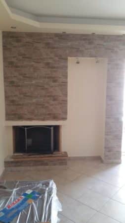 επένδυση τοίχου σαλονιού με πλακίδια τύπου πέτρας γύρω από τζάκι σε ανακαίνιση κατοικίας