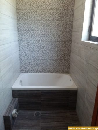 Μικρό μπάνιο με μπανιέρα και επένδυση τοίχου με πλακάκια μωσαϊκού