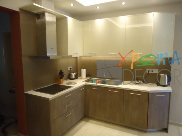 Ανακαίνιση κουζίνας στα Κάτω Πετράλωνα με γωνιακή σύνθεση, ντουλάπια σε απόχρωση ξύλου και λευκό πάγκο