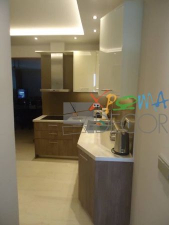 Ανακαίνιση κουζίνας στα Κάτω Πετράλωνα με λευκό πάγκο και ντουλάπια σε απόχρωση φυσικού ξύλου