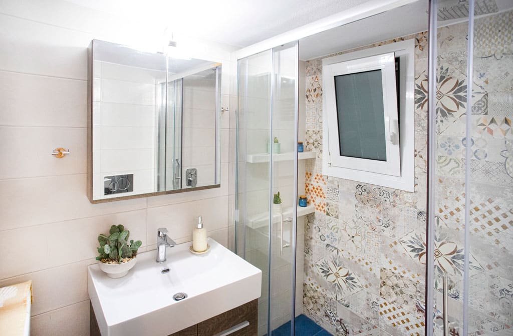 Ανακαίνιση μπάνιου στην Καλλιθέα με καμπίνα ντους, ξύλινο έπιπλο νιπτήρα και ρετρό πλακάκια