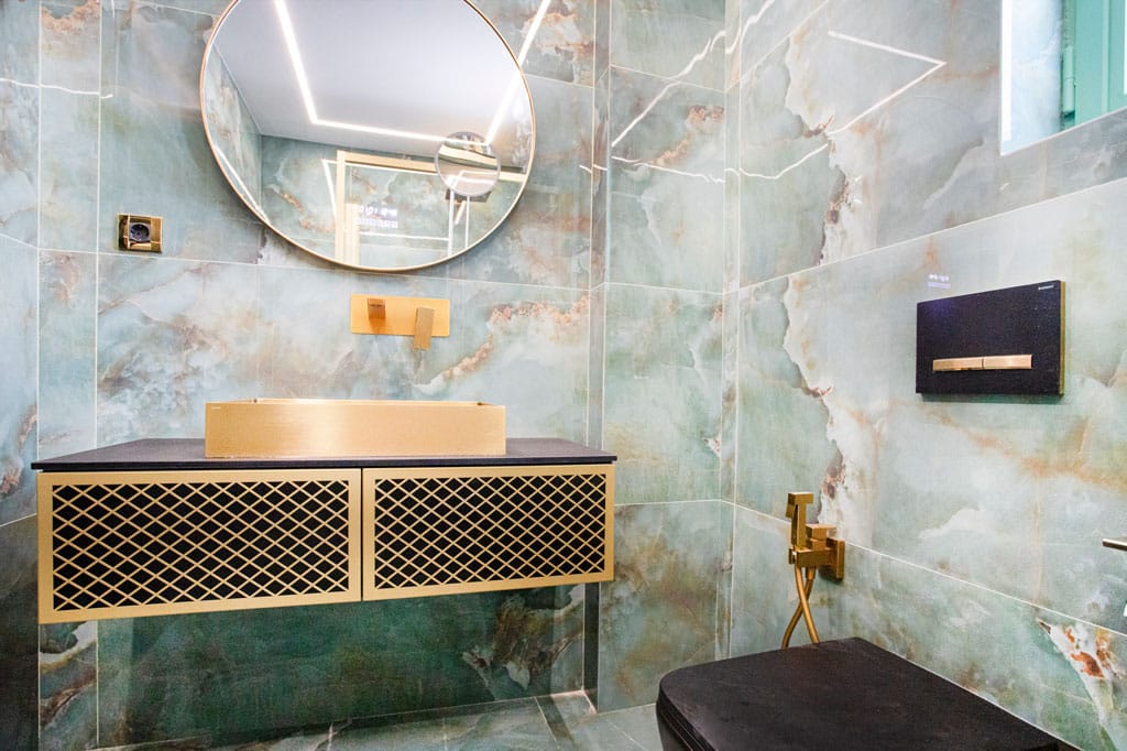 Μοντέρνο μπάνιο με κρεμαστό έπιπλο, χρυσό νιπτήρα, στρογγυλό καθρέφτη και πλακίδια τύπου όνυχα σε ανακαίνιση στα Πατήσια