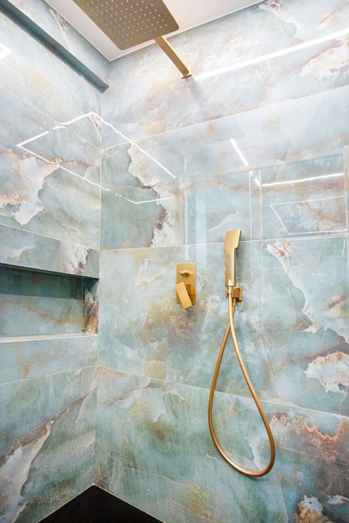Λεπτομέρεια ντους σε μπάνιο στα Πατήσια με πλακίδια τύπου όνυχα, χρυσή εντοιχισμένη μπαταρία, rain shower και κρυφό LED φωτισμό