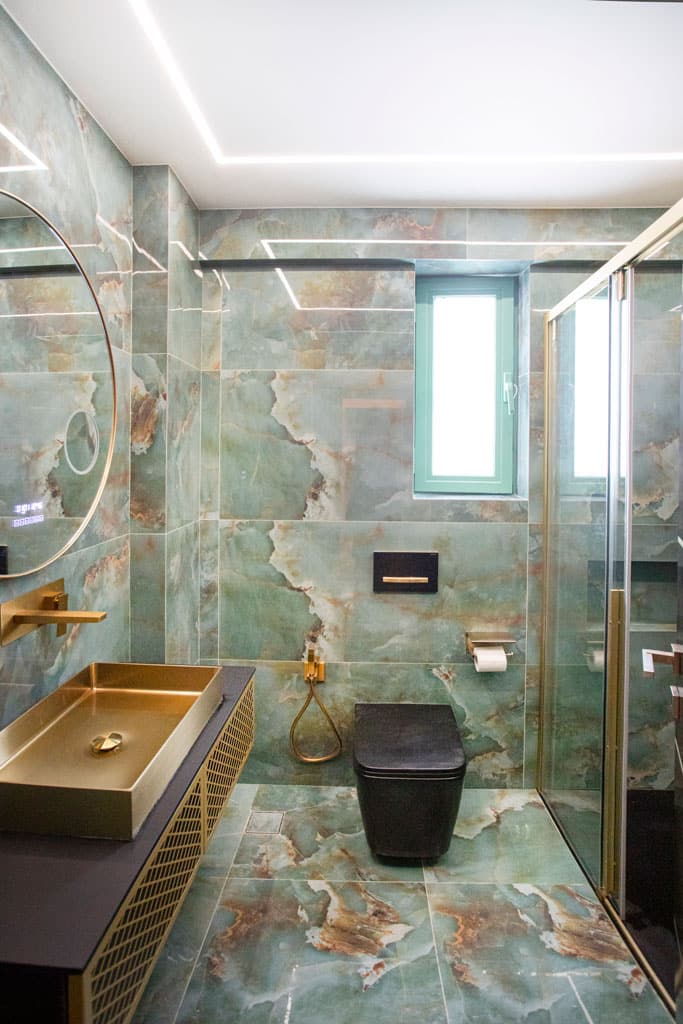 Ολοκληρωμένη ανακαίνιση μπάνιου στα Πατήσια με πλακίδια τύπου όνυχα, χρυσά είδη υγιεινής, γυάλινη καμπίνα ντους και κρυφό φωτισμό LED