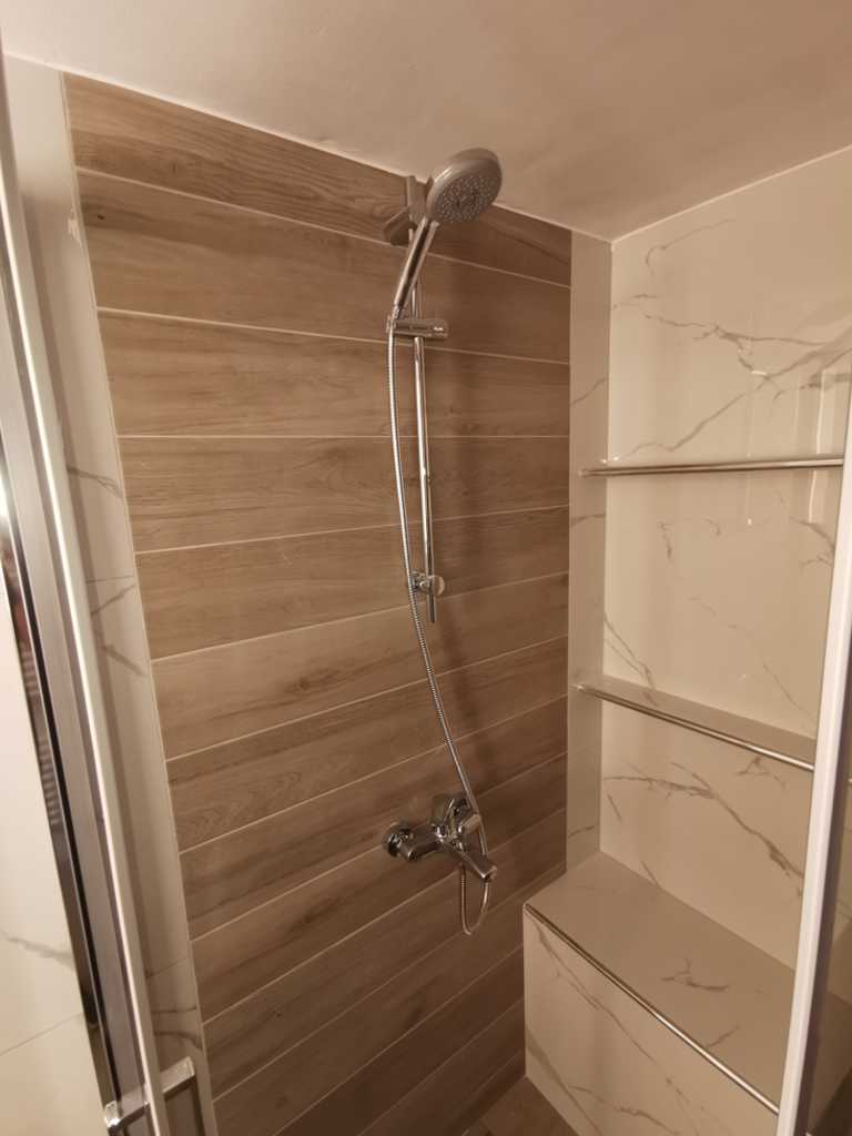 Ντουζιέρα με εντοιχισμένο ράφι και επένδυση πλακιδίων απομίμησης ξύλου σε ανακαίνιση μπάνιου στον Ταύρο