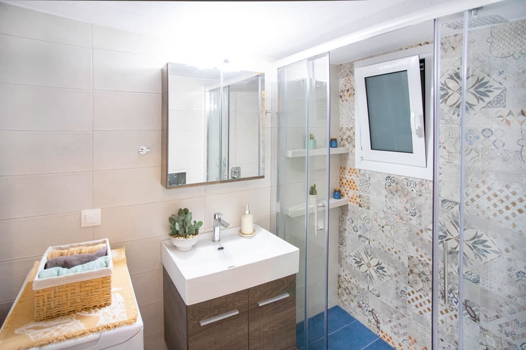 Ανακαινισμένο μπάνιο στην Καλλιθέα με ξύλινο έπιπλο νιπτήρα και καμπίνα ντους με ρετρό πλακάκια