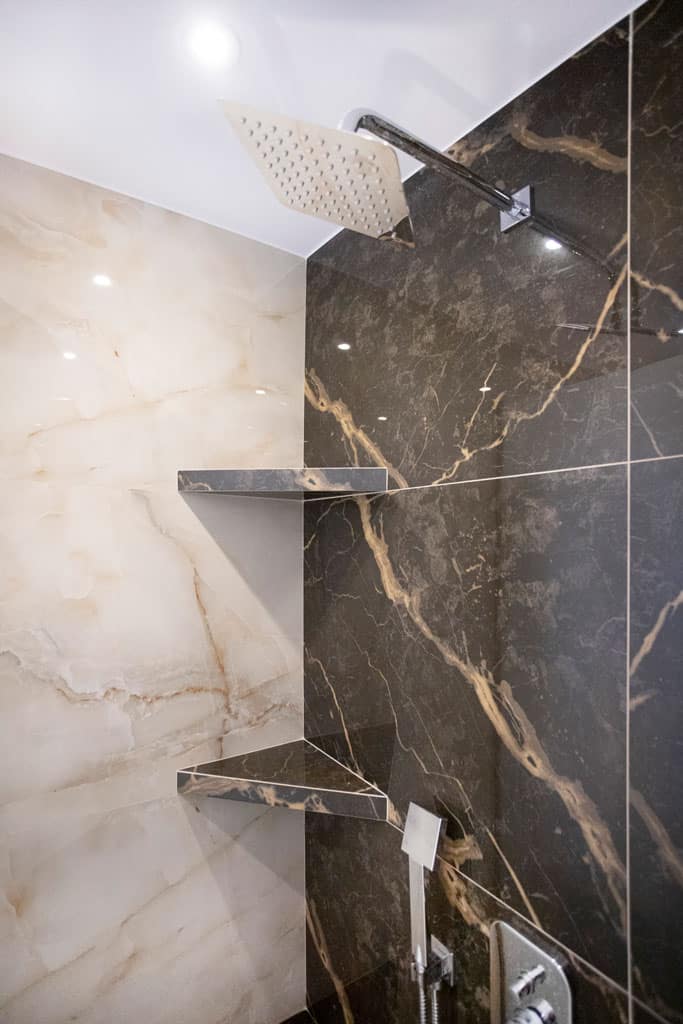 Ντουζιέρα με εντοιχισμένα ράφια και μαύρο πλακάκι σε ανακαίνιση μπάνιου στον Πειραιά