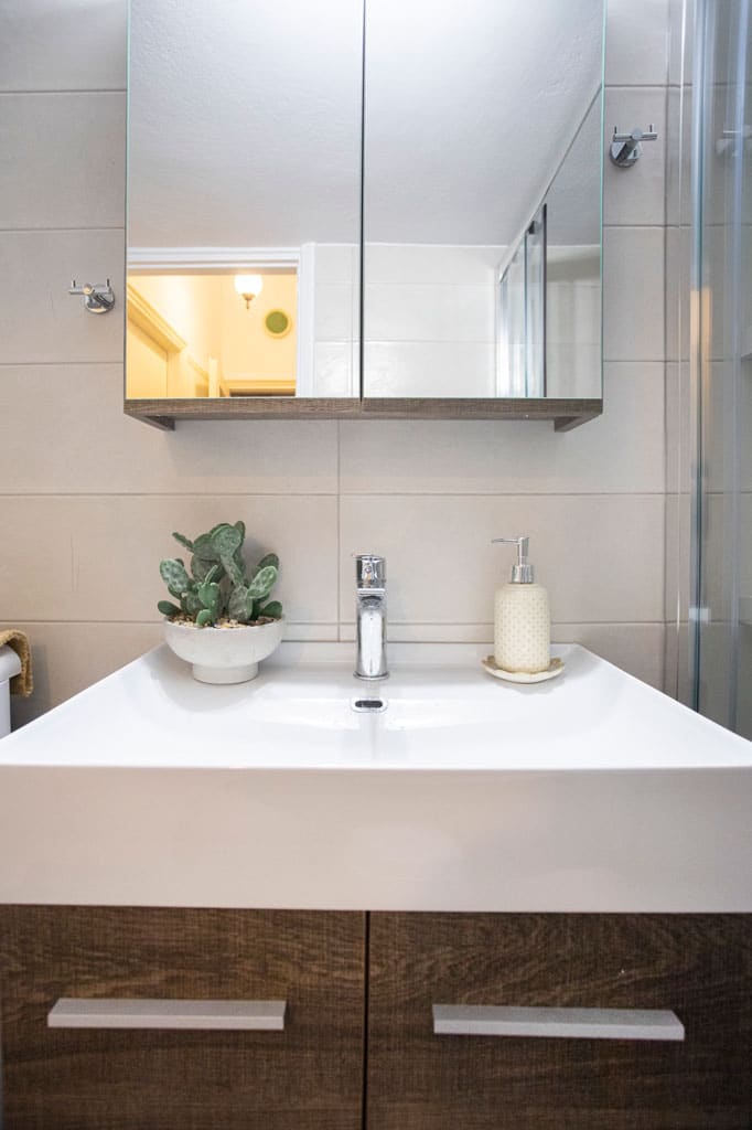 Ξύλινο έπιπλο μπάνιου με λευκό νιπτήρα και καθρέφτη σε ανακαινισμένο μπάνιο