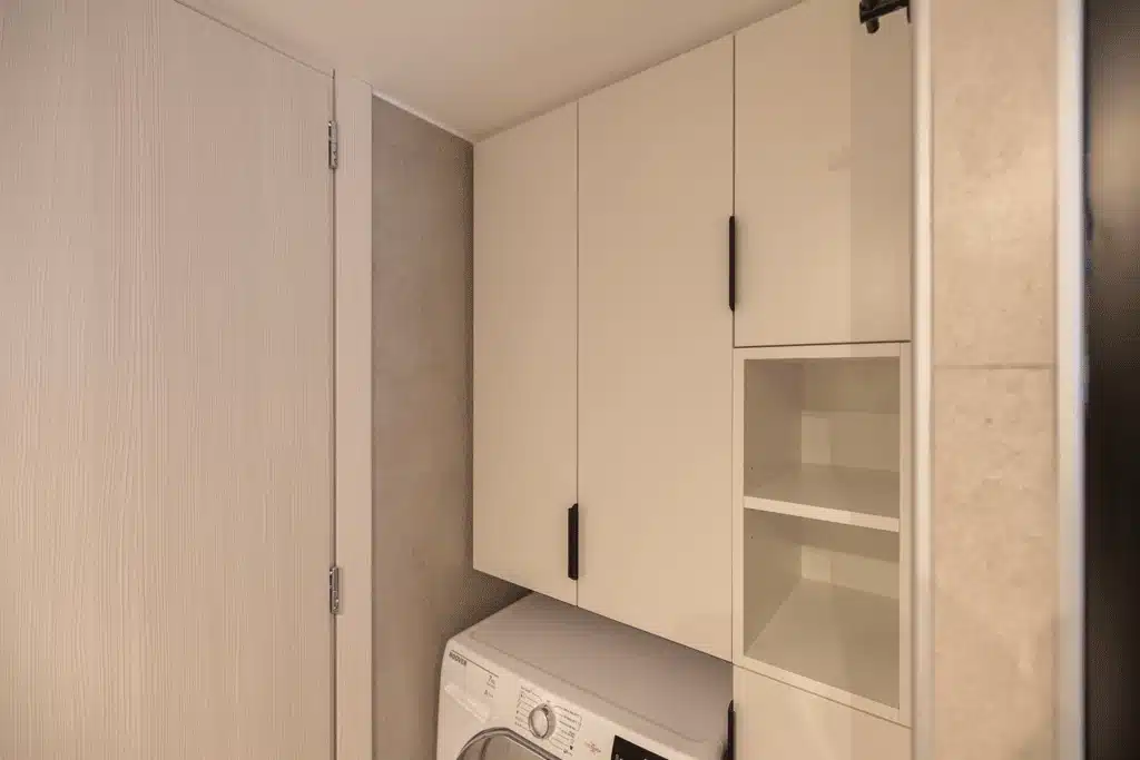 Έπιπλο μπάνιου με ντουλάπια και ράφια πάνω από πλυντήριο ρούχων σε σύγχρονη ανακαίνιση