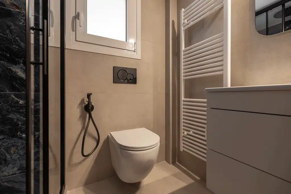 Κρεμαστή λεκάνη με εντοιχισμένο καζανάκι και μπεζ πλακάκια σε σύγχρονη ανακαίνιση μπάνιου