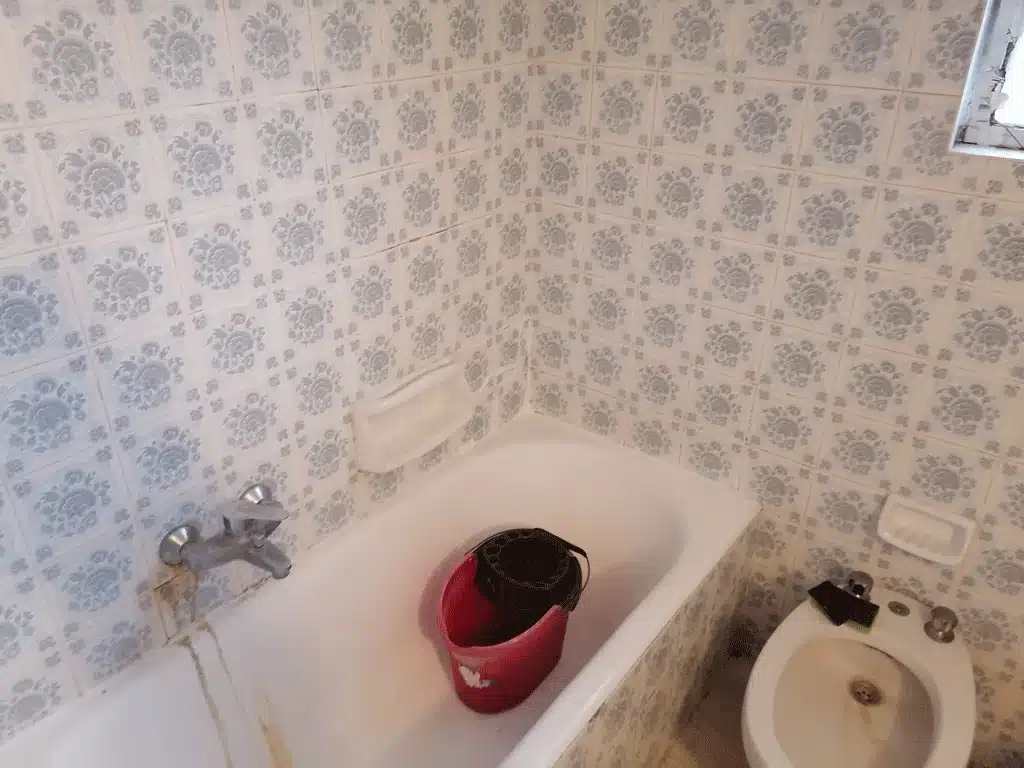 Παλιό μπάνιο πριν την ανακαίνιση με μπανιέρα, ρετρό πλακάκια τοίχου και εμφανείς φθορές