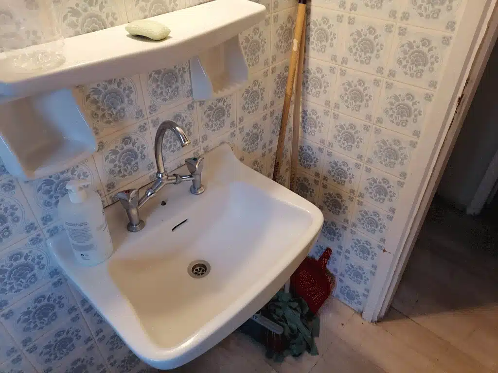 Παλαιό μπάνιο πριν την ανακαίνιση με παλιό νιπτήρα και διακοσμητικά πλακάκια τοίχου
