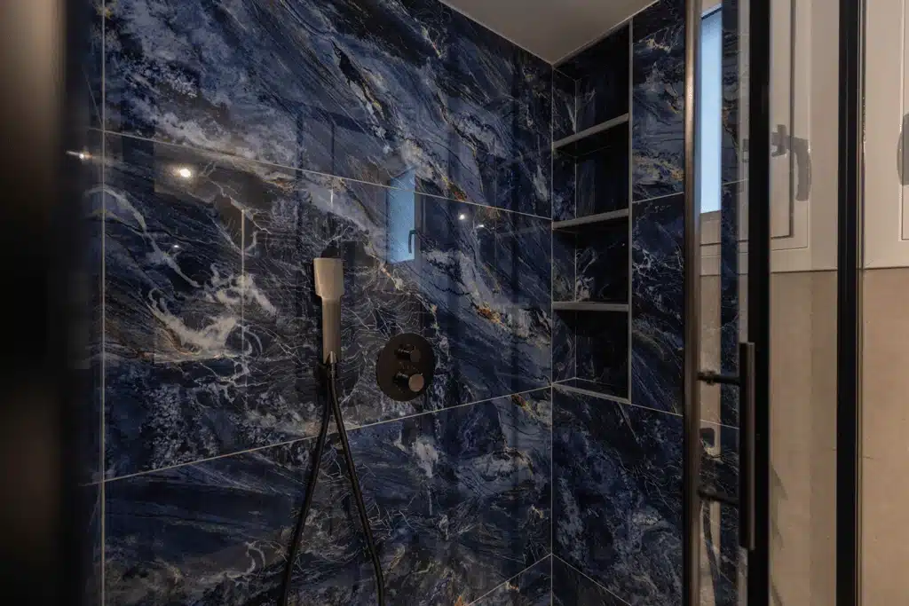 Μαύρη εντοιχισμένη μπαταρία ντους σε μπάνιο με μπλε marble πλακάκια και εντοιχισμένη εσοχή