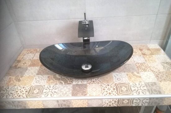 μαύρος γυάλινος νιπτήρας μπάνιου σε πάγκο με διακοσμητικά πλακάκια σε ανακαίνιση μπάνιου στα Κάτω Πετράλωνα