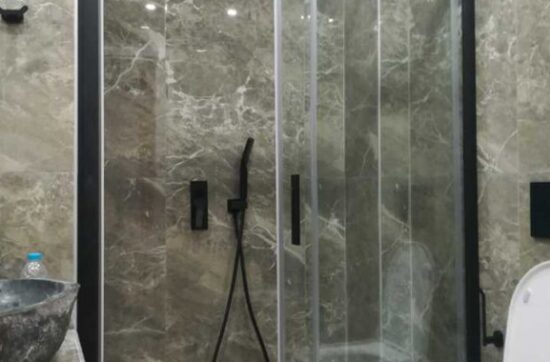 Ντουζιέρα με μαύρη καμπίνα και μαρμάρινη επένδυση τοίχου σε ανακαίνιση μπάνιου στον Ταύρο από τη Chroma Decor