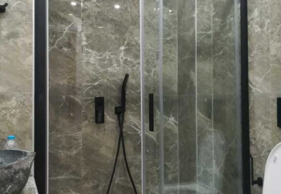 Ντουζιέρα με μαύρη καμπίνα και μαρμάρινη επένδυση τοίχου σε ανακαίνιση μπάνιου στον Ταύρο από τη Chroma Decor