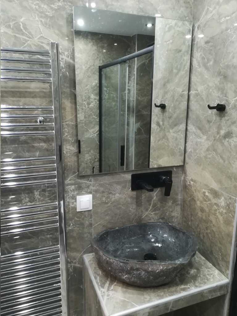 Πέτρινος νιπτήρας τοποθετημένος σε χτιστό πάγκο με μαύρη εντοιχισμένη μπαταρία σε ανακαίνιση μπάνιου στον Ταύρο από τη Chroma Decor