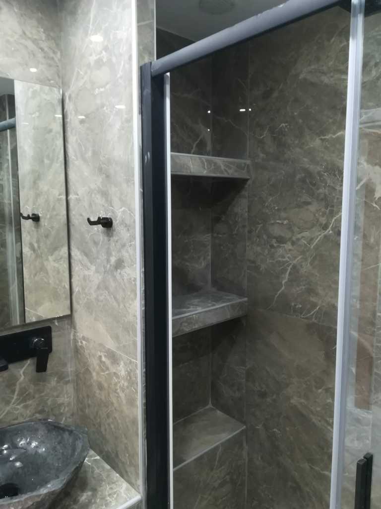 Χτιστά ράφια σε ντουζιέρα με πλακάκια μαρμάρινης υφής σε ανακαίνιση μπάνιου στον Ταύρο