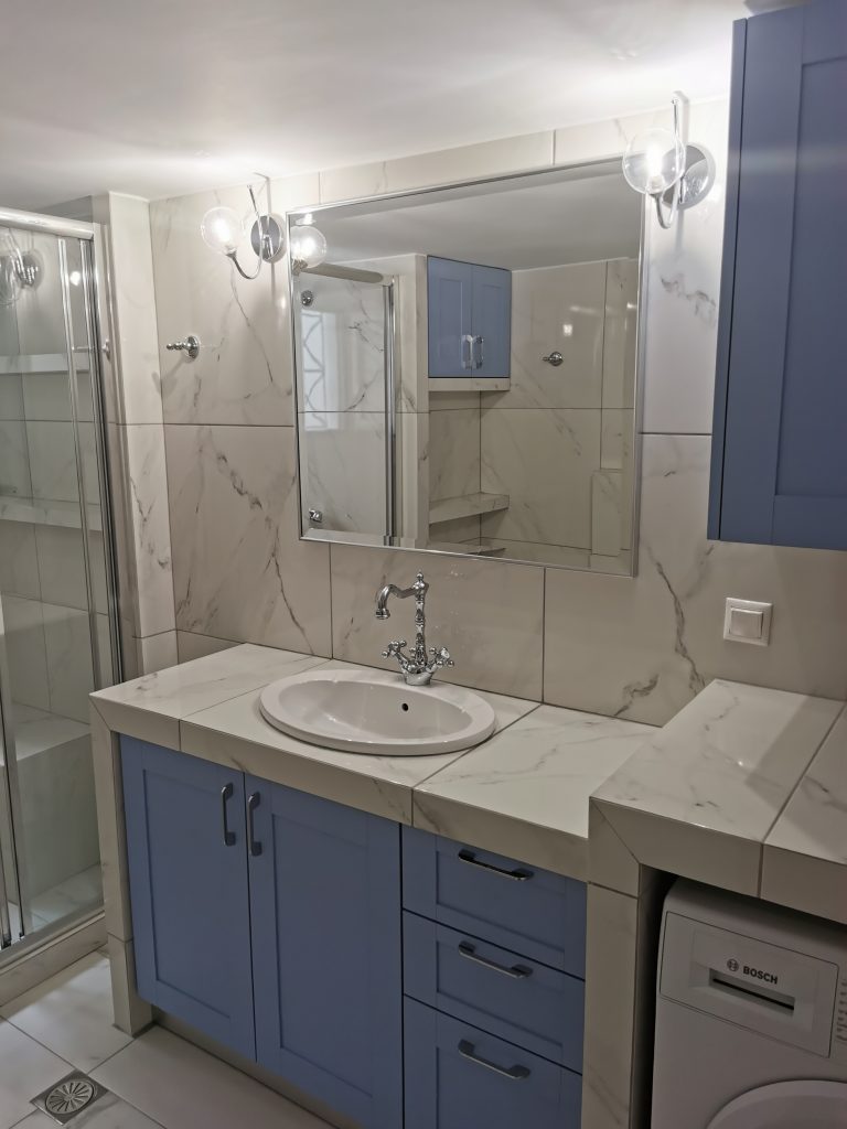 Ολική ανακαίνιση μπάνιου στο Παγκράτι με μπλε έπιπλο, custom πάγκο και ενσωματωμένο πλυντήριο