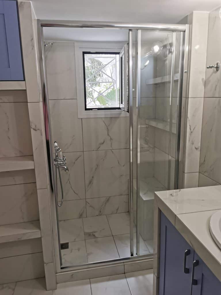 Γυάλινη καμπίνα ντουζιέρας σε ανακαινισμένο μπάνιο στο Παγκράτι με πλακάκια μαρμάρινης υφής