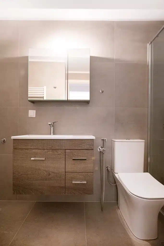 Ανακαινισμένο μπάνιο στη Νίκαια με ξύλινο έπιπλο νιπτήρα, καθρέφτη και σύγχρονο WC