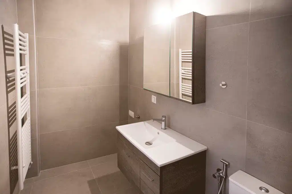 Μοντέρνο μπάνιο στη Νίκαια με κρεμαστό έπιπλο νιπτήρα, καθρέφτη-ντουλάπι και γκρι πλακάκια