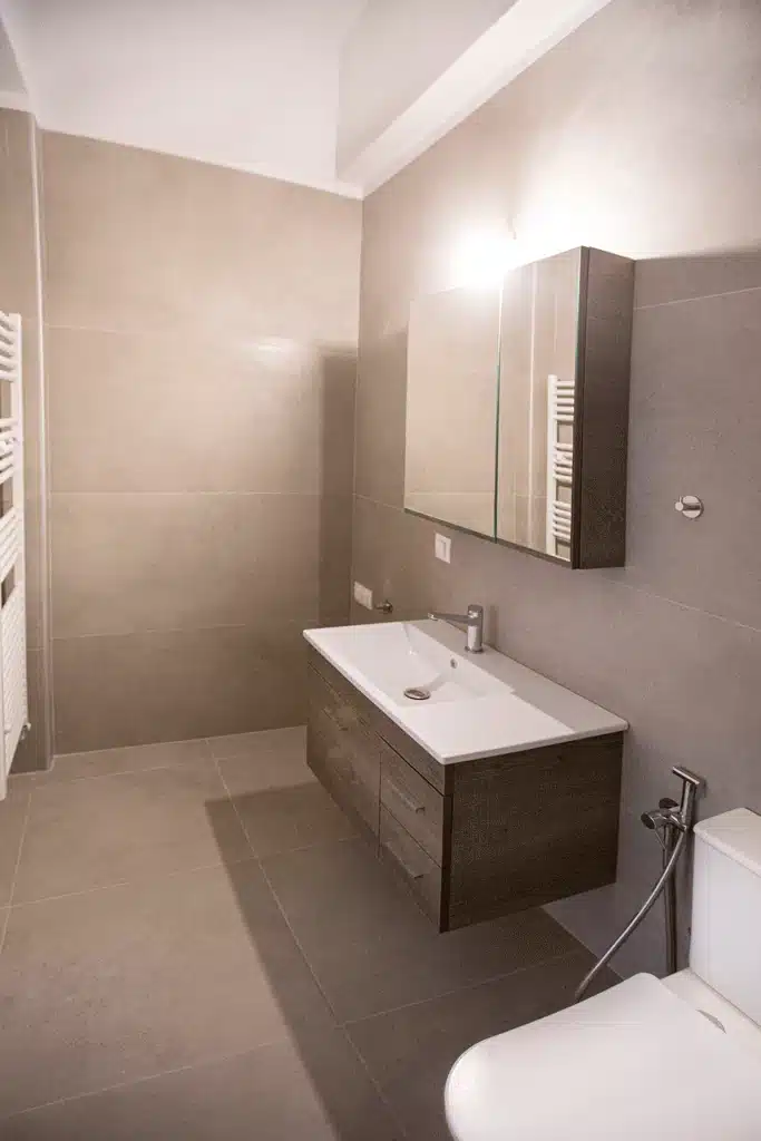 Ανακαινισμένο μπάνιο στη Νίκαια με μεγάλο κρεμαστό έπιπλο νιπτήρα και γκρι πλακάκια