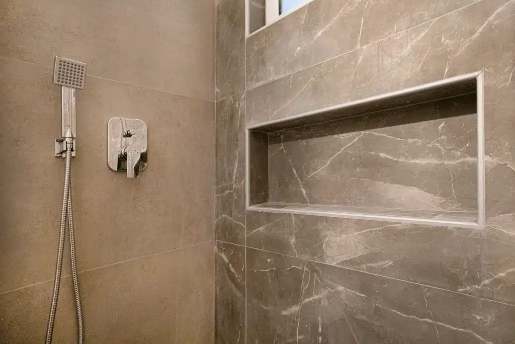 Εντοιχισμένη εσοχή αποθήκευσης σε ντους με πλακάκια τύπου μαρμάρου σε ανακαινισμένο μπάνιο στη Νίκαια