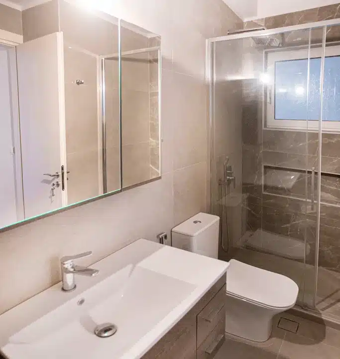Ανακαινισμένο μπάνιο στη Νίκαια με ενθέτο νιπτήρα, σύγχρονο WC και γυάλινη καμπίνα ντους