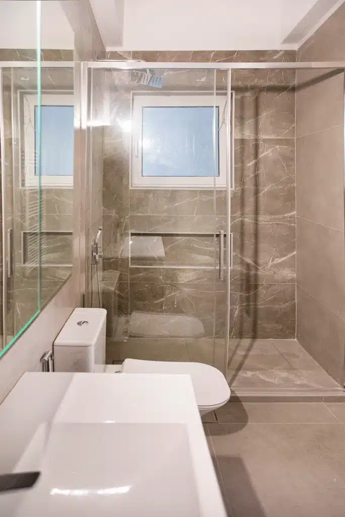 Μοντέρνο μπάνιο στη Νίκαια με γυάλινη καμπίνα ντους και επένδυση πλακιδίων τύπου μαρμάρου
