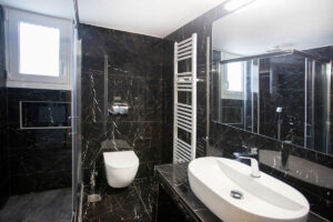 Ανακαίνιση μπάνιου στον Άλιμο με μαύρα πλακάκια τύπου μαρμάρου, κρεμαστή λεκάνη και καμπίνα ντους