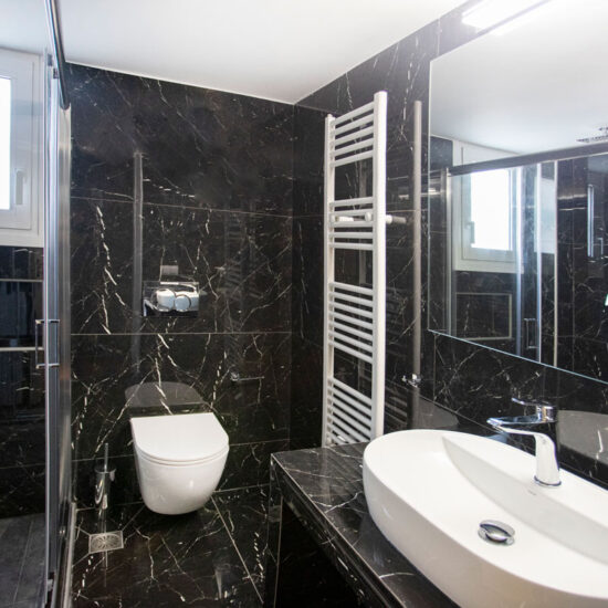 Ανακαίνιση μπάνιου στον Άλιμο με μαύρα πλακάκια τύπου μαρμάρου, κρεμαστή λεκάνη και καμπίνα ντους