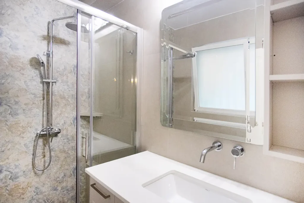 Νιπτήρας, καθρέφτης και ντουζιέρα σε ανακαινισμένο μπάνιο στη Γλυφάδα